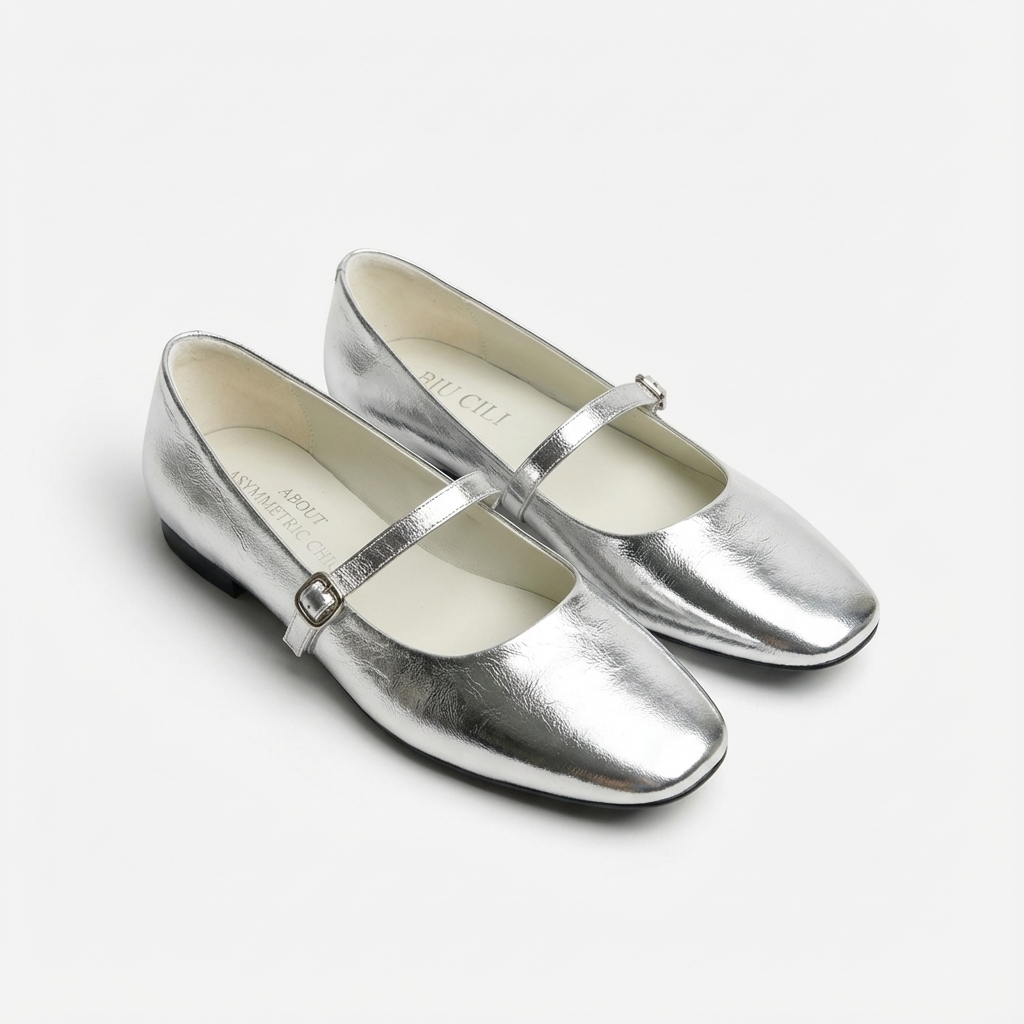 Pair of silver shoes with a strap on a white background